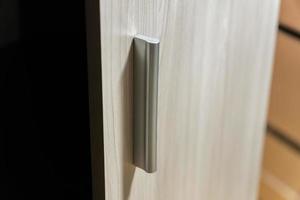 Kleiderschrank offene Tür. Nahaufnahme der Holztür mit Metallgriff foto