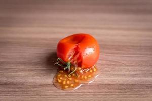 Zertrümmerte Tomate auf Holztisch foto
