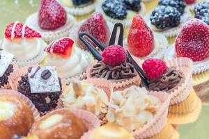 verschiedene kleine süße Kuchen mit Vanille, Schokolade, Erdbeere, Brombeere und Zuckerpulver foto