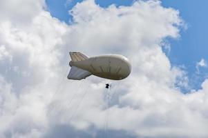 Weißes Luftschiff eines weichen Systems mit Stabilisatoren und einem Motor schwebt am Himmel foto