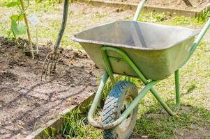 gartenschubkarre in der nähe von gartenbeet und werkzeugen foto