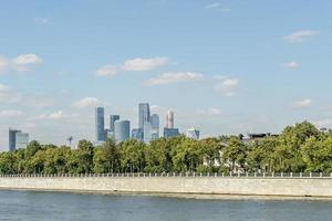 blick auf das ufer des moskauer flusses und die wolkenkratzer der stadt moskau hinter den bäumen foto