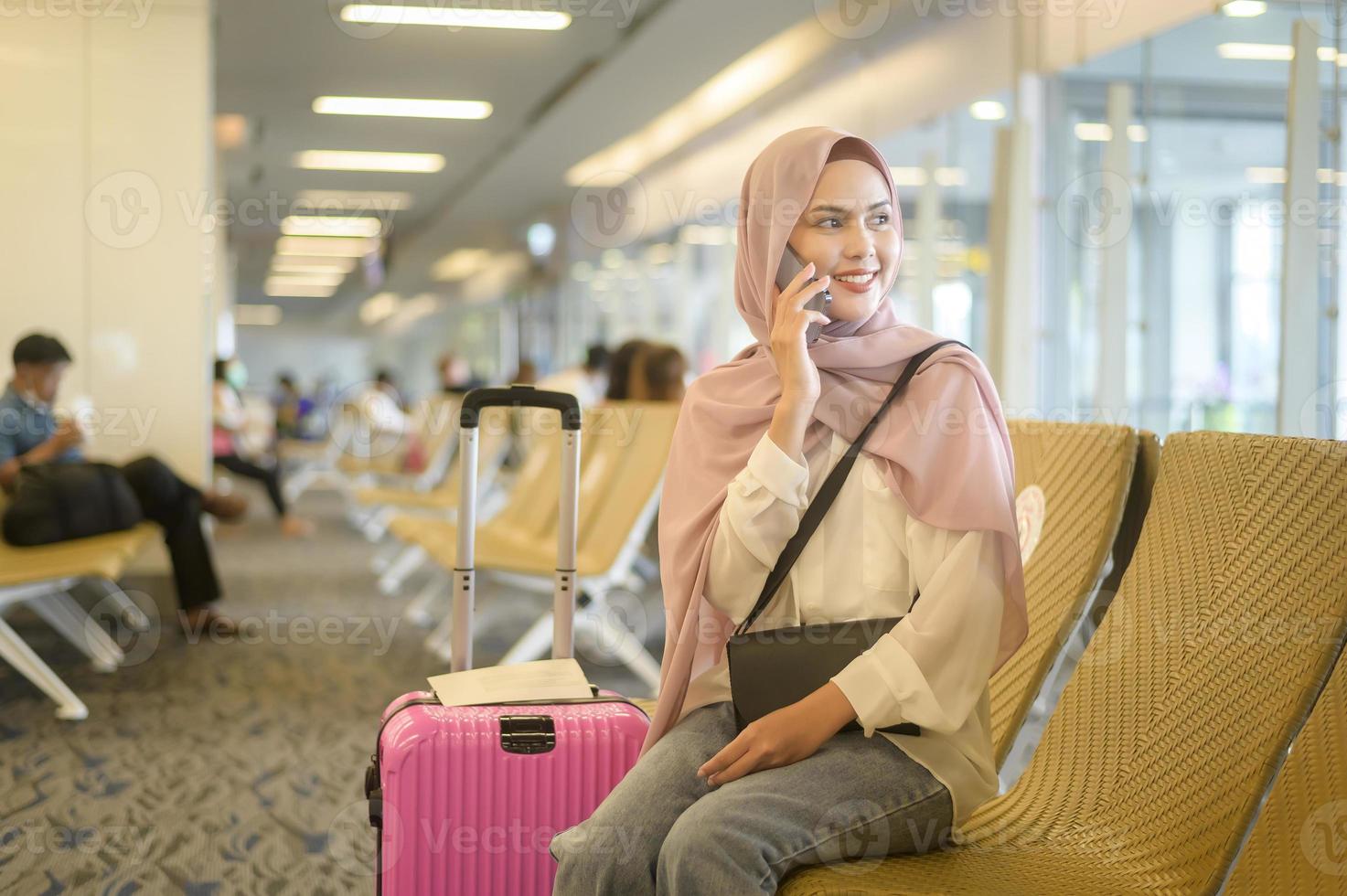 ung kvinnlig muslimsk resenär som bär resväskor på den internationella flygplatsen, resor, semester och resa koncept. foto