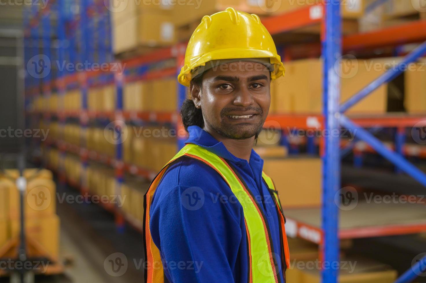 porträtt av ung blandras manlig arbetare bär hjälm i moderna lager lagring av butik foto