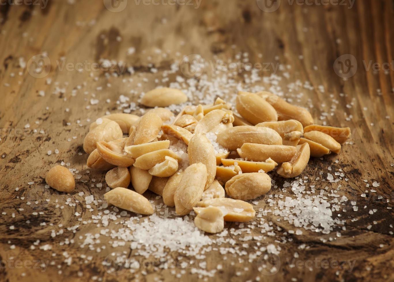 rostade jordnötter och salt i en skål på träbakgrund foto