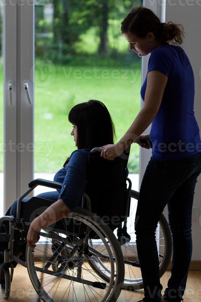 vårdgivare som driver rullstol med funktionshindrad kvinna foto