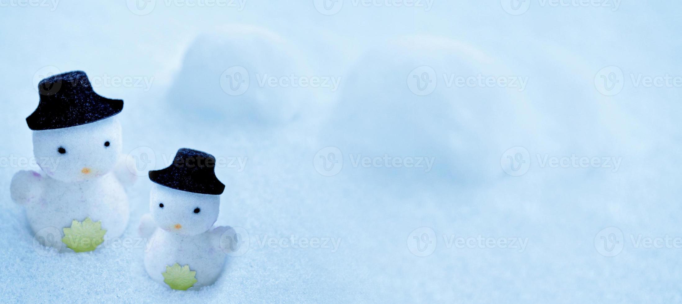 vit snögubbe i en svart hatt i snön. foto