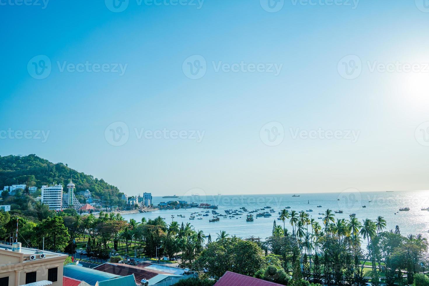 vung tau stadens flygfoto med vacker solnedgång och så många båtar. panoramautsikt över kustnära vung tau från ovan, med vågor, kustlinje, gator, kokospalmer och tao phung-berget i vietnam. foto