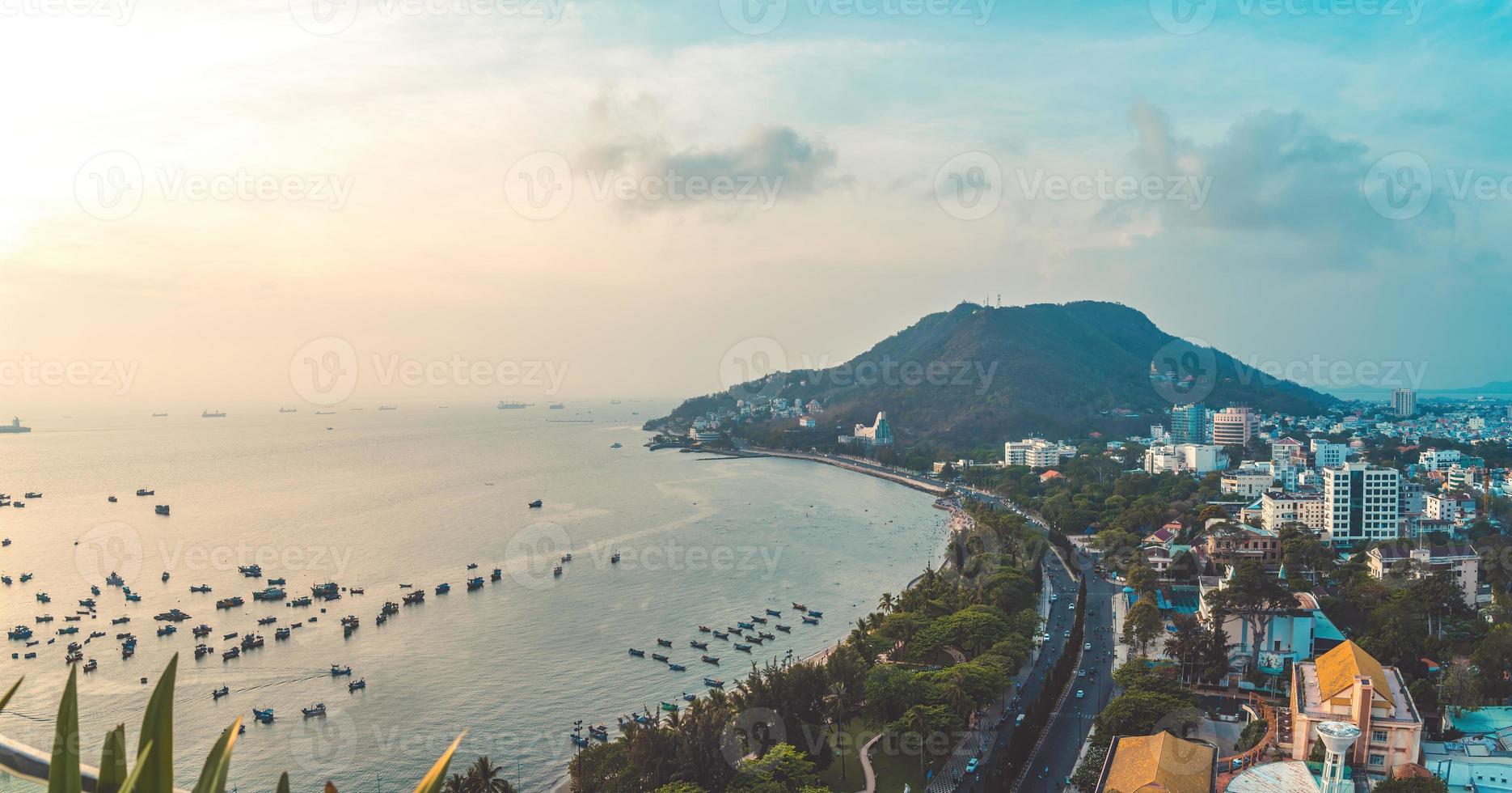 vung tau stadens flygfoto med vacker solnedgång och så många båtar. panoramautsikt över kustnära vung tau från ovan, med vågor, kustlinje, gator, kokospalmer och tao phung-berget i vietnam. foto