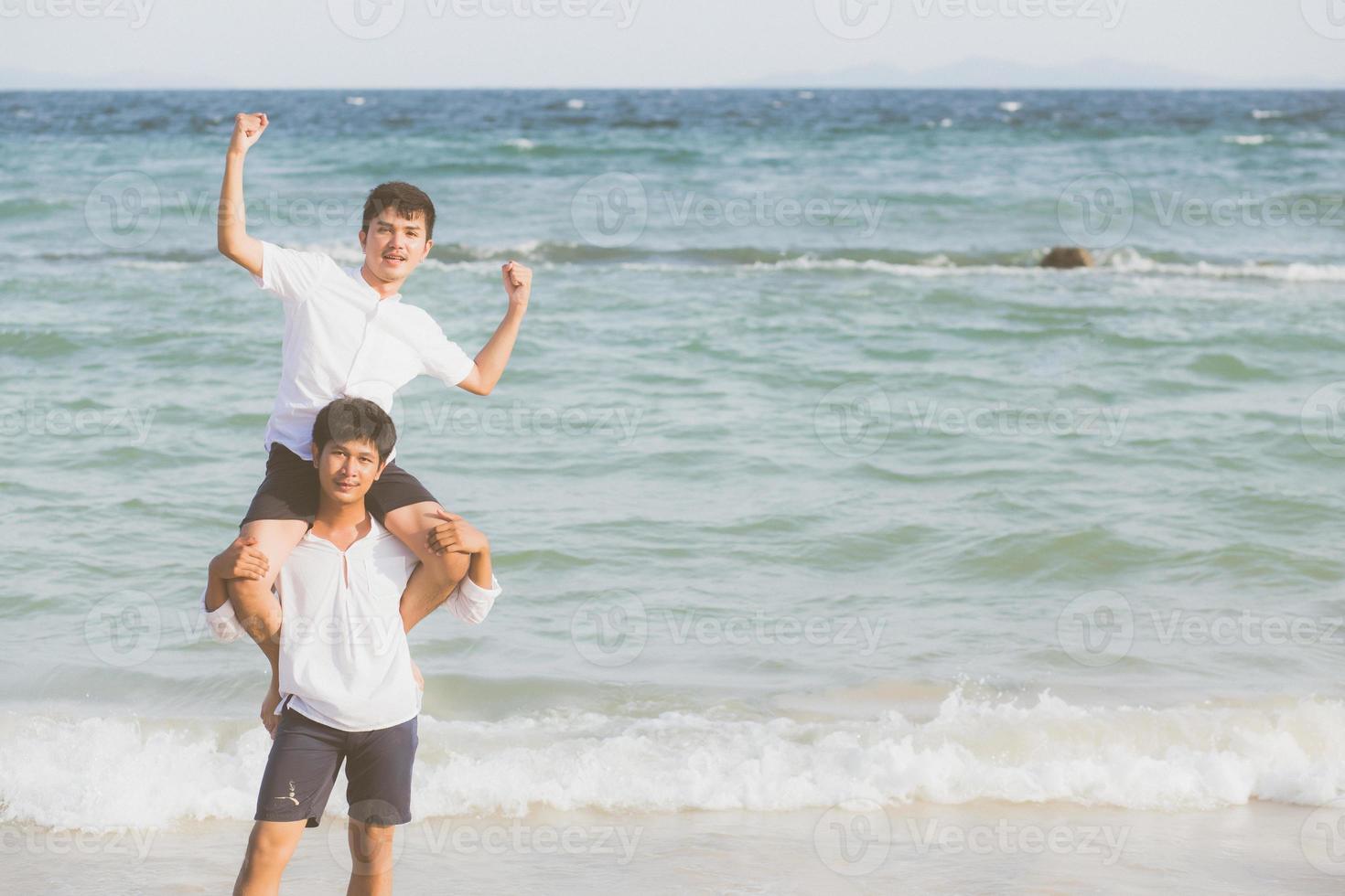 homosexuella porträtt ungt asiatiskt par rider halsen tillsammans med njuta och kul på stranden på sommaren, asien gay glada gå havet för fritid med romantisk och lycklig semester till sjöss, hbt med juridiska. foto