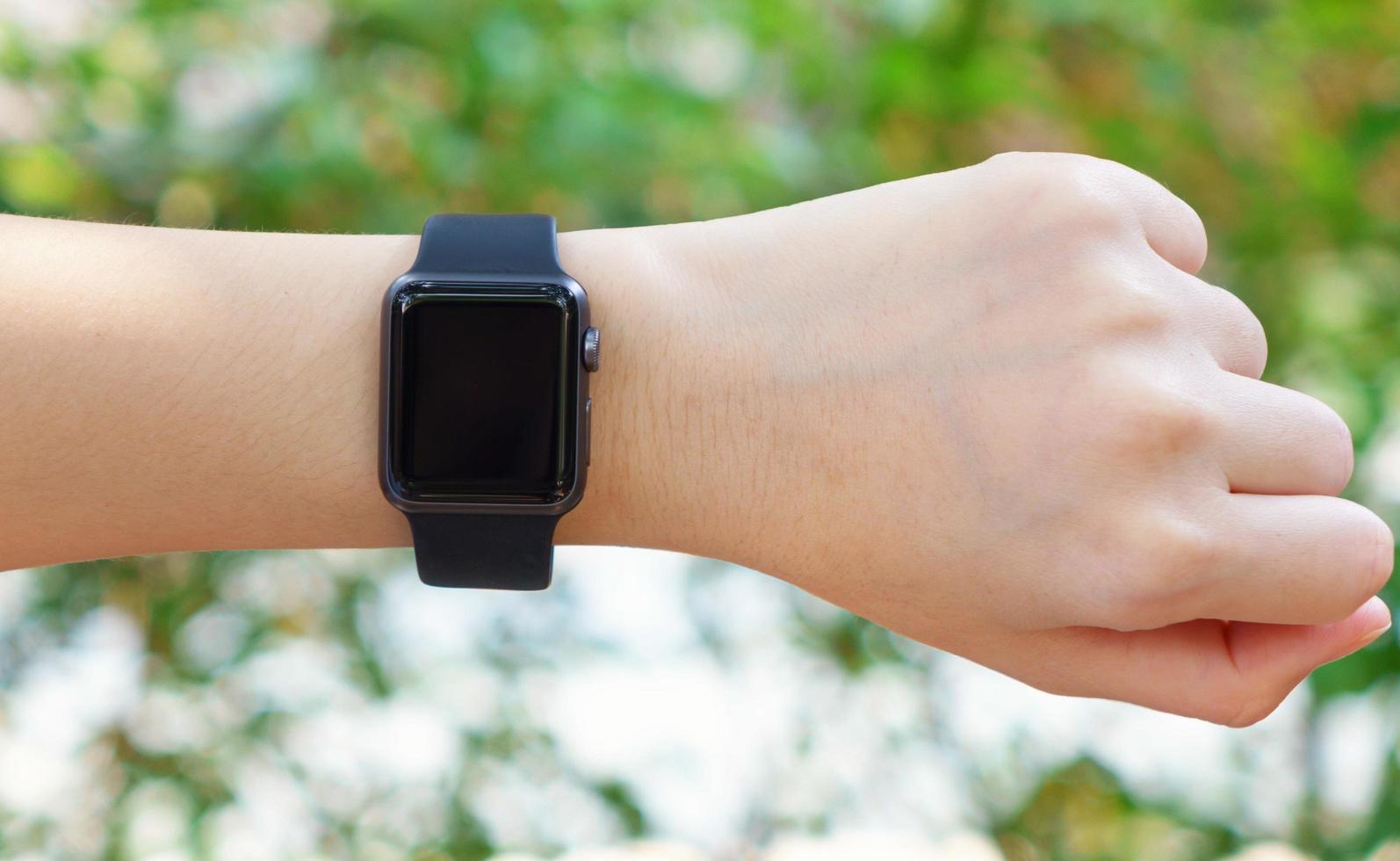 kvinnlig hand med smart klocka i naturbakgrund foto