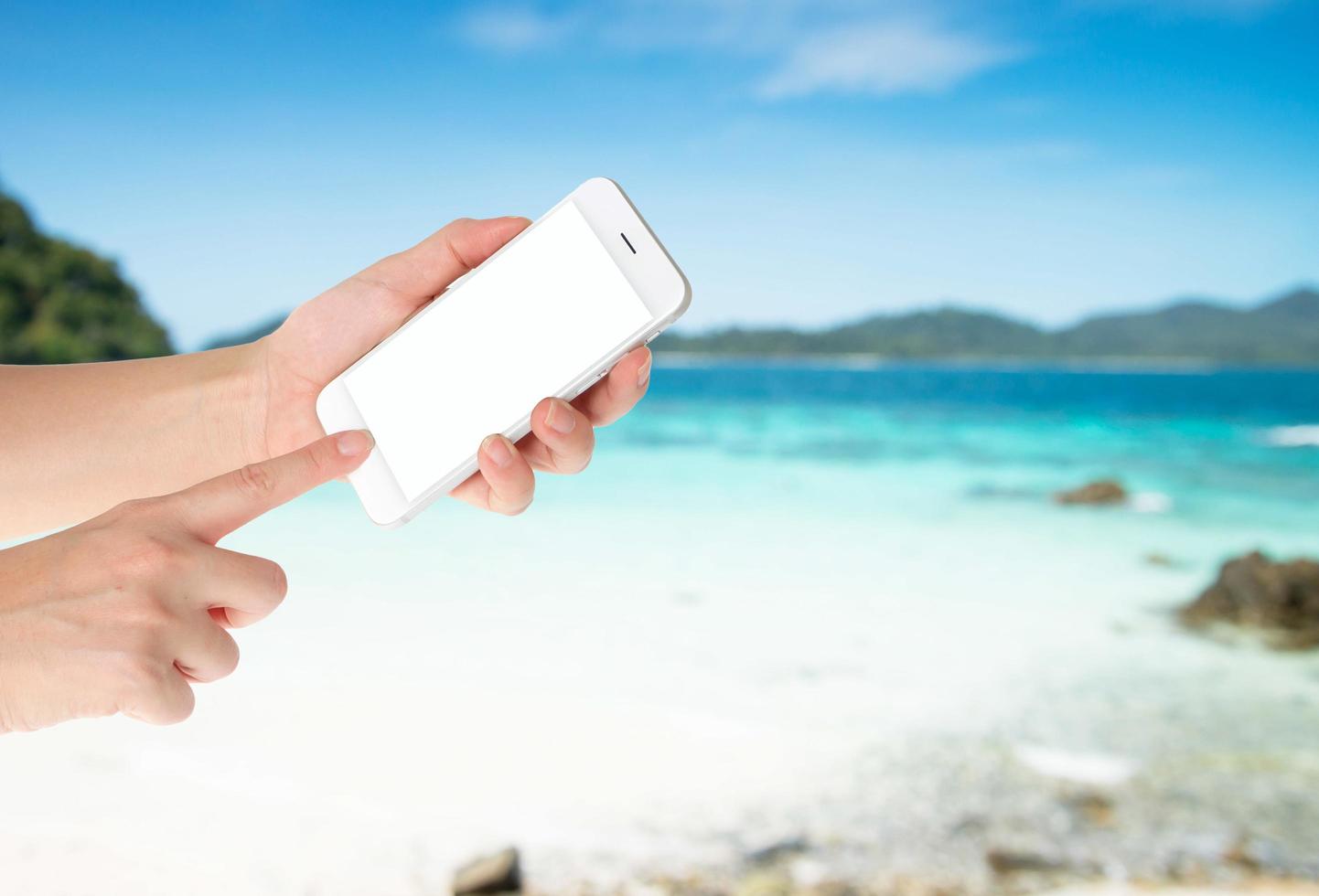 kvinna hand visar smart telefon med isolerade skärmar visas på stranden bakgrund foto
