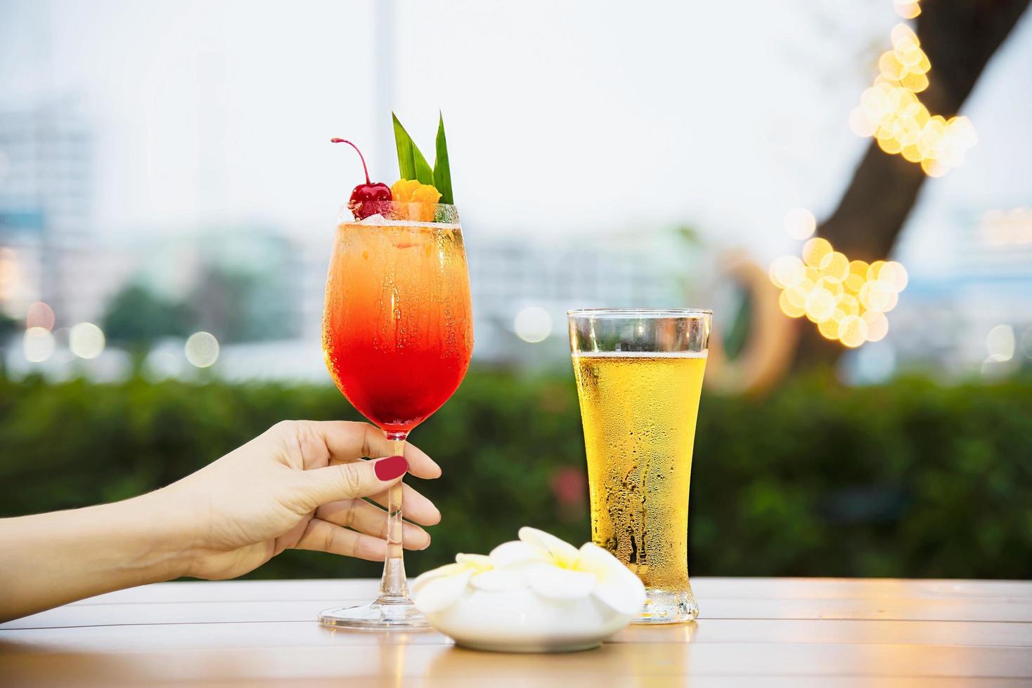 människor firande i restaurang med öl och mai tai eller mai thai - glad livsstil människor med glad drink i trädgårdskoncept foto