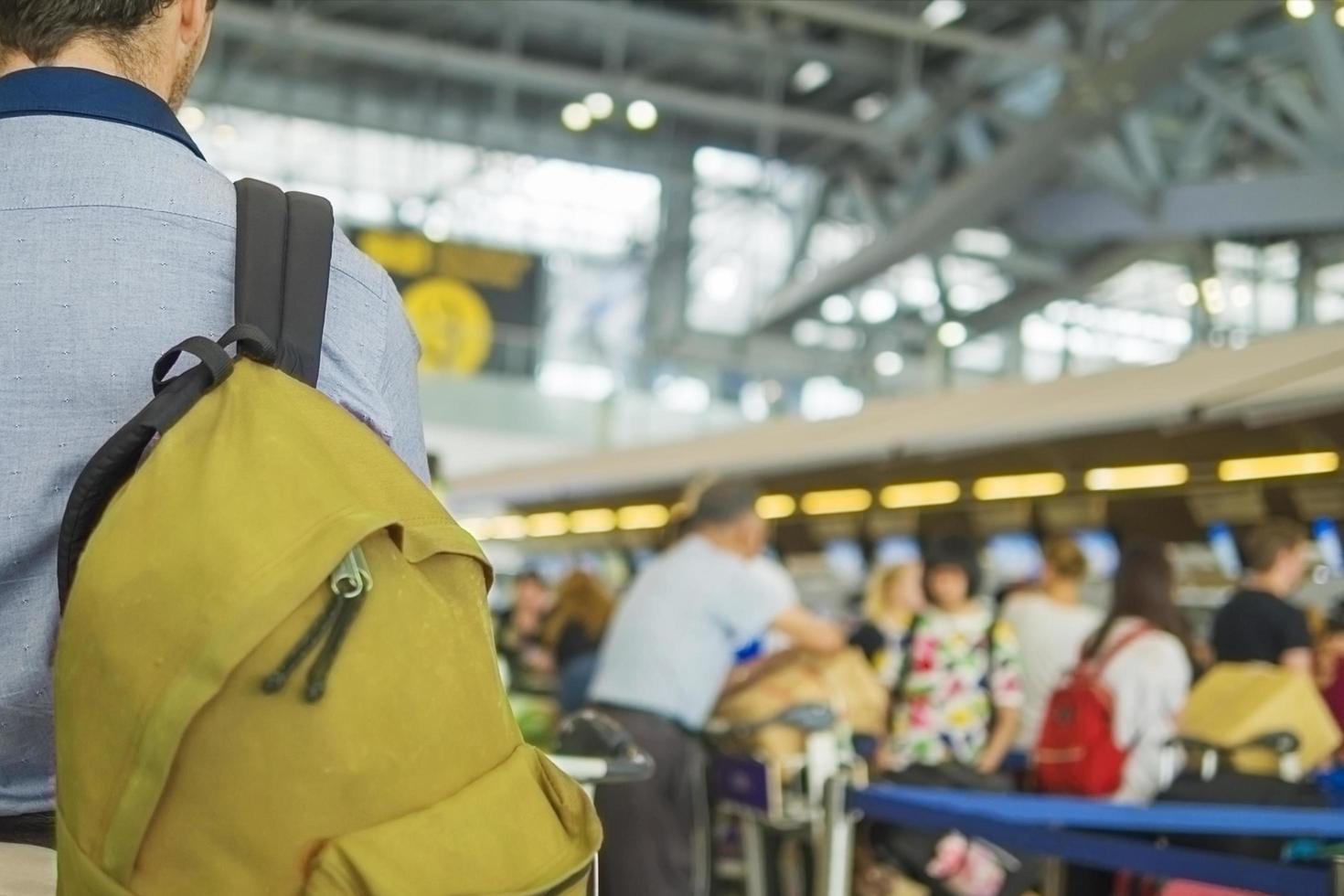 mjukt fokuserad bild av resenär över suddig lång passagerarkö som väntar på incheckning vid flygplatsens incheckningsdiskar foto