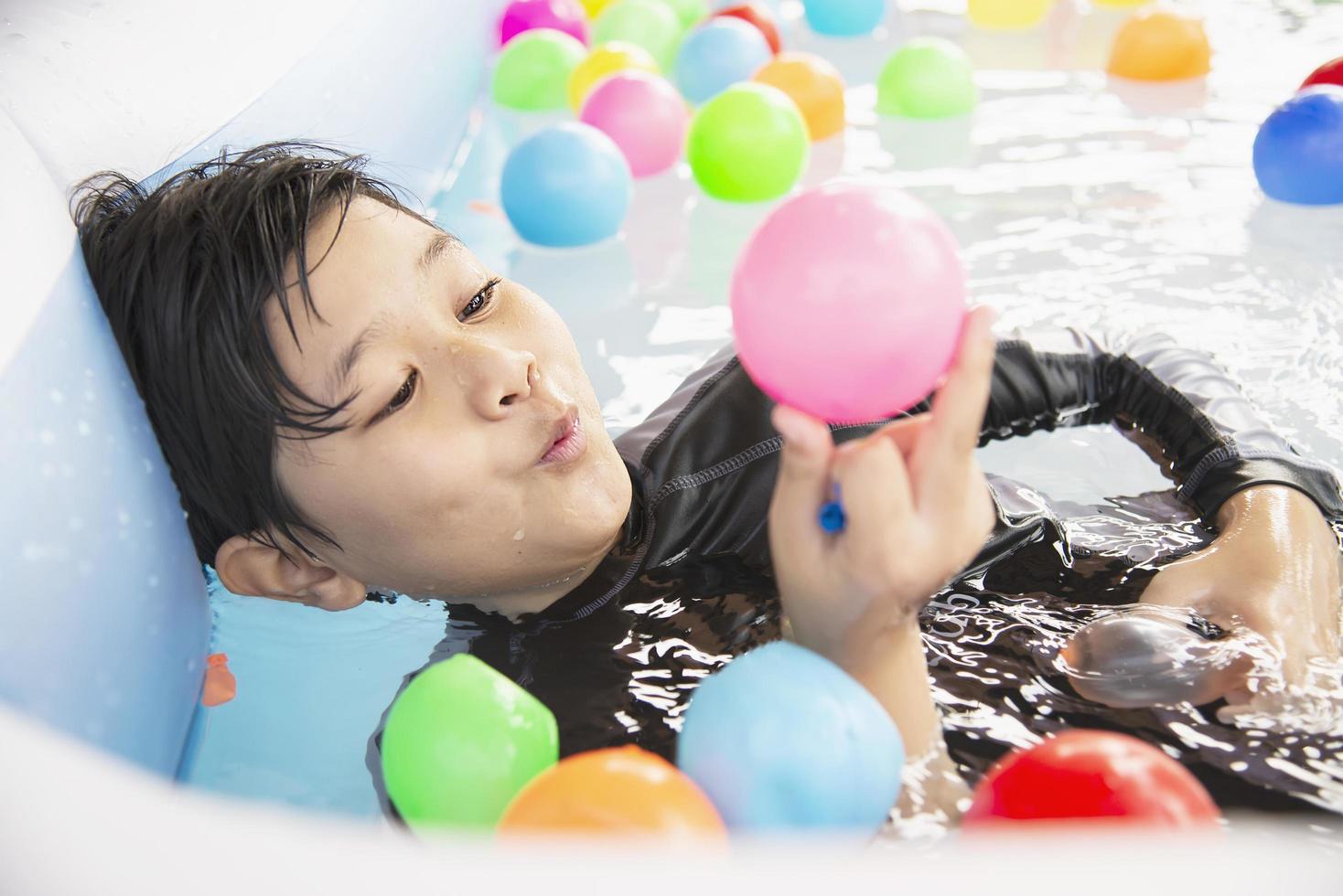 pojke leker med färgglada boll i liten pool leksak - glad pojke i vatten pool leksak koncept foto