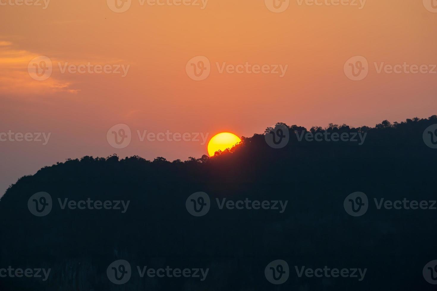 soluppgången bakom bergen, bergens skuggor, den orangea himlen med svaga moln. foto