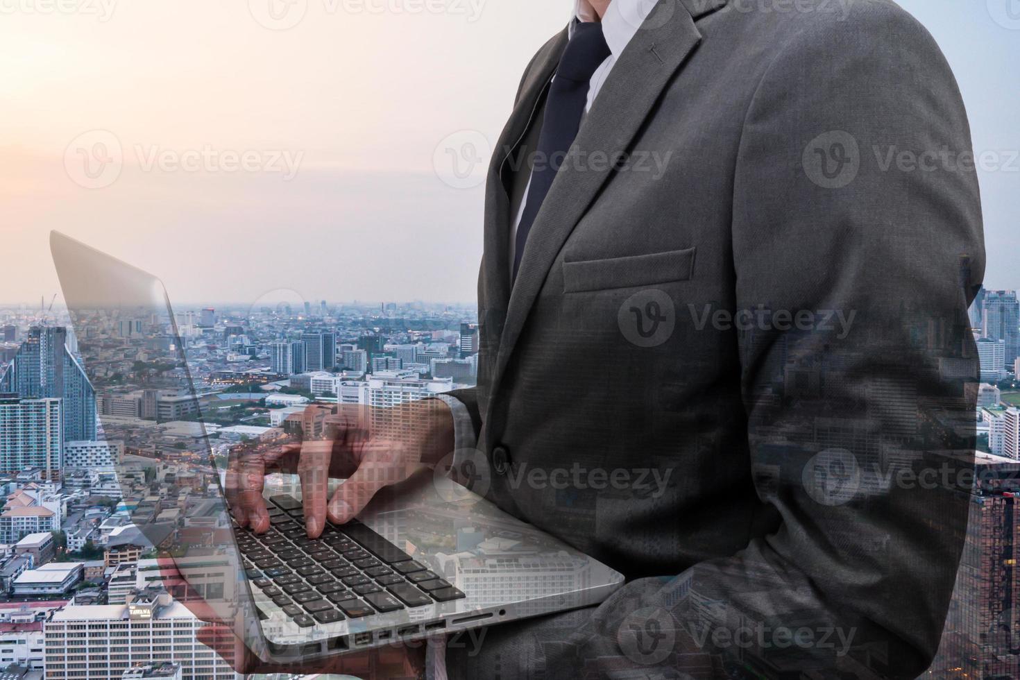 dubbelt exponerad av affärsman som håller laptop med stadsbilden. foto