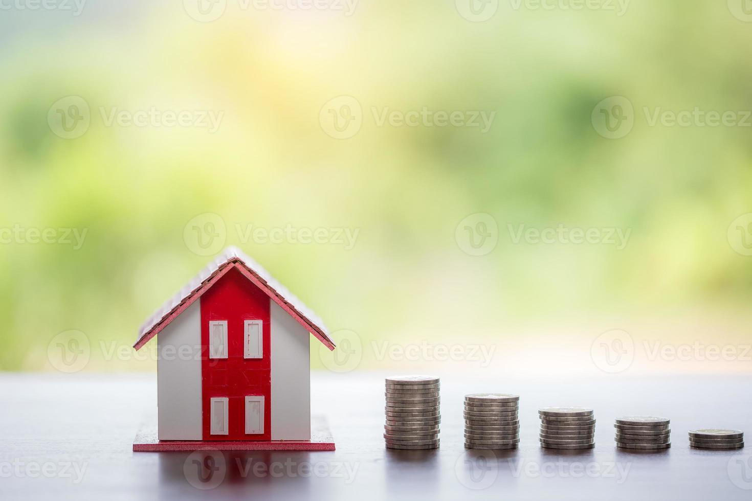 hus modell och pengar mynt staplar med oskärpa natur bakgrund. sparplaner för hem, lån, investeringar, bolån, finans och bank om huskoncept. foto