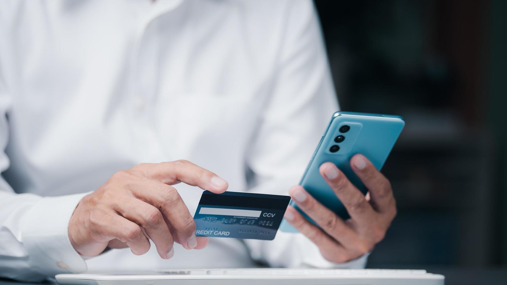 ung affärsman som använder kreditkort för att göra finansiella transaktioner via smartphone, betalningskoncept med trådlös kommunikationsteknik, fokus på konsumentsäkerhet och kontantlöshet. foto