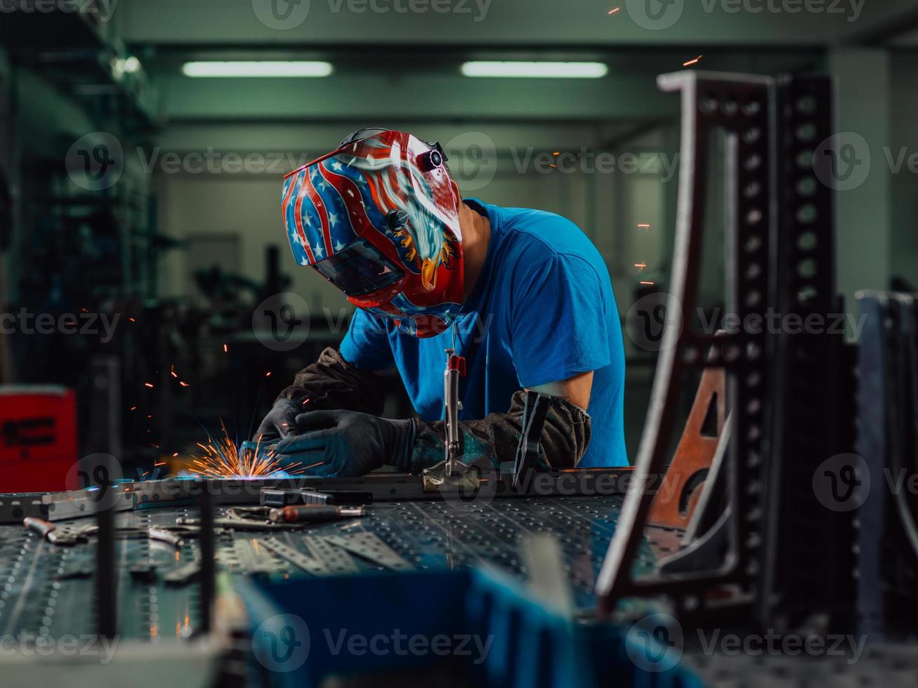 professionell tungindustrisvetsare som arbetar inne i fabriken, bär hjälm och börjar svetsa. selektiv fokusering foto