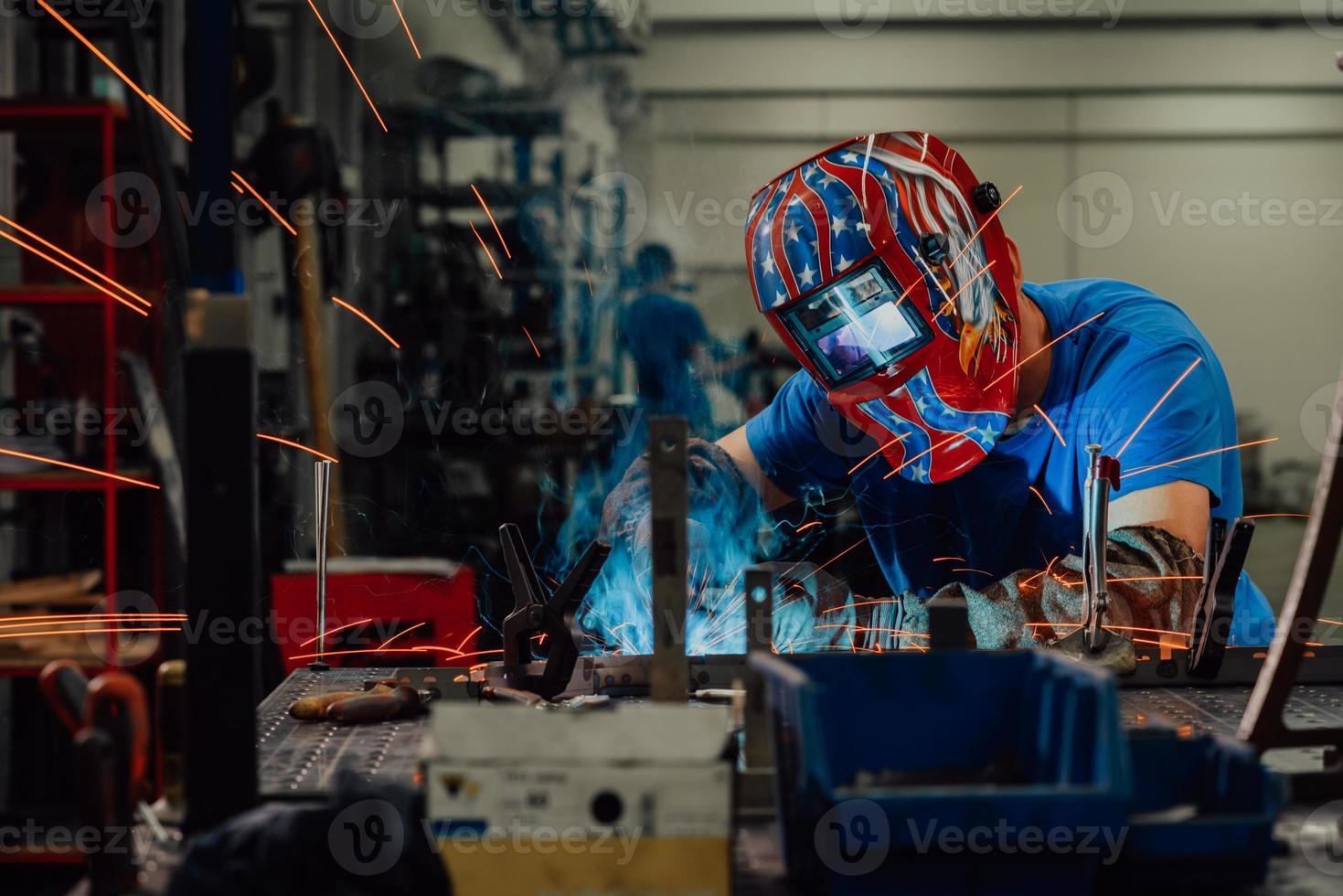 professionell tungindustrisvetsare som arbetar inne i fabriken, bär hjälm och börjar svetsa. selektiv fokusering foto