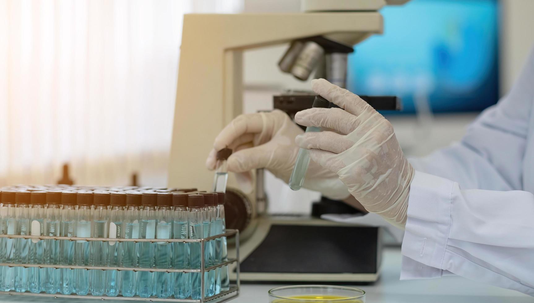 biokemi laboratorieforskning, kemist analyserar prov i laboratorium med mikroskoputrustning och vetenskapsexperiment glas som innehåller kemisk vätska. foto