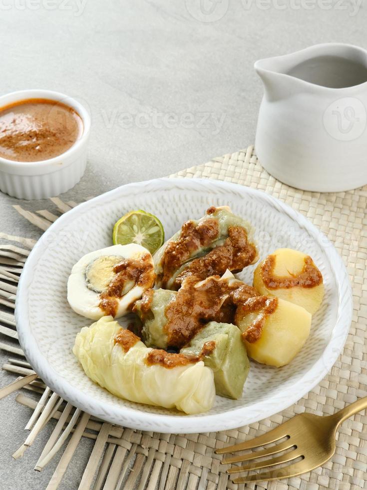 siomay bandung, ångade klimpar med kokt ägg, tofu, potatis och kålrulle. indonesisk traditionell gatumat med jordnötssås och sojasås, serverad med grön lime. foto