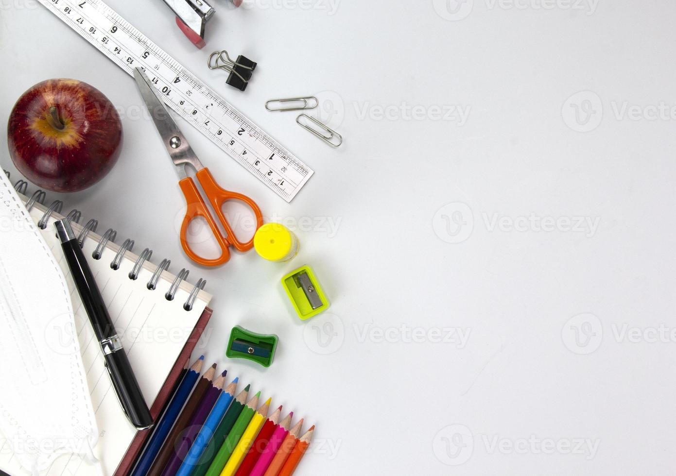 utbildning element koncept, färgpennor, ansiktsmask, gem, sax, linjal, äpple isolerad på vit bakgrund. tillbaka till skolan koncept foto