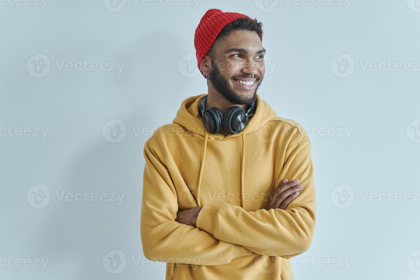 stilig afrikansk man håller armarna i kors och ler medan han står mot väggen foto