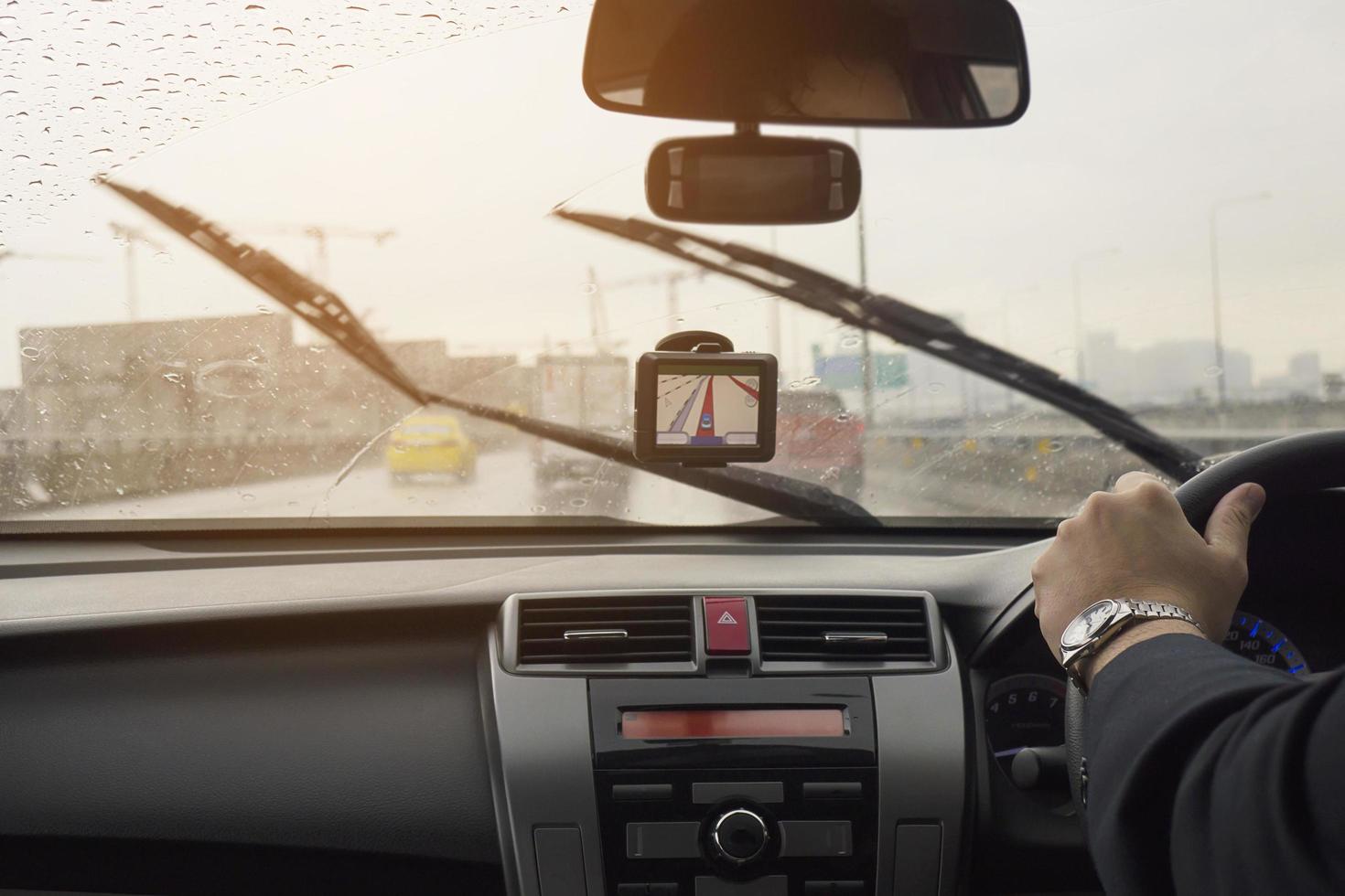 affärsman kör bil i en regnig dag med rörliga torkarblad foto