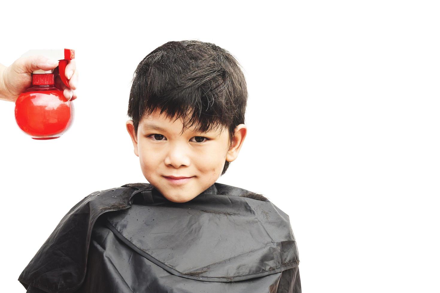 en pojke sprayas hans hår av frisör isolerade över vit bakgrund foto
