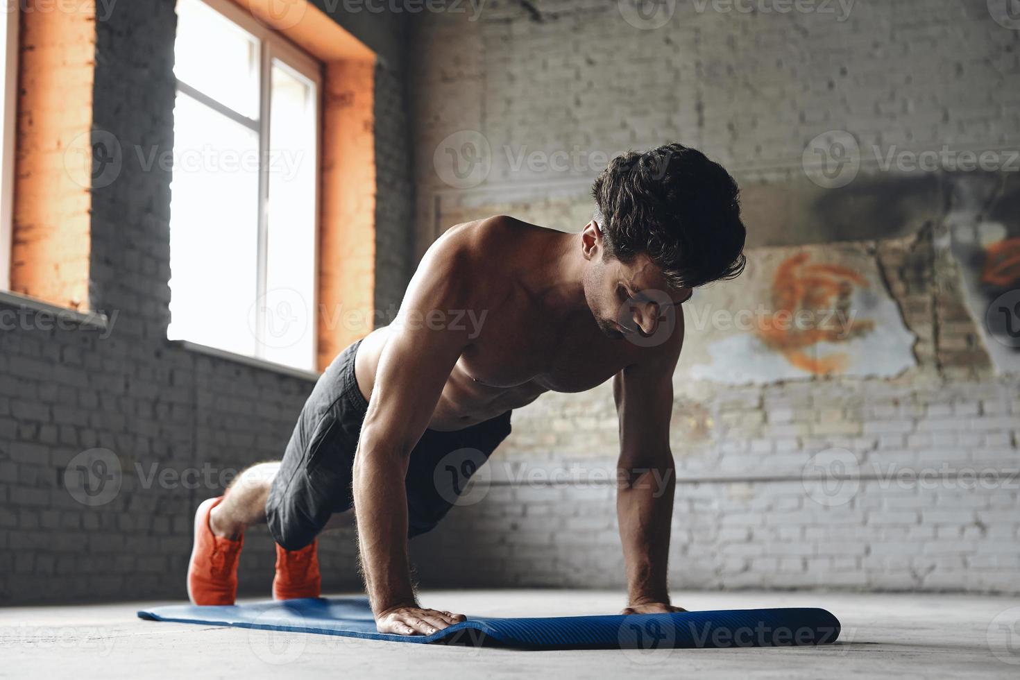 koncentrerad ung man gör push-up övningar i gymmet foto