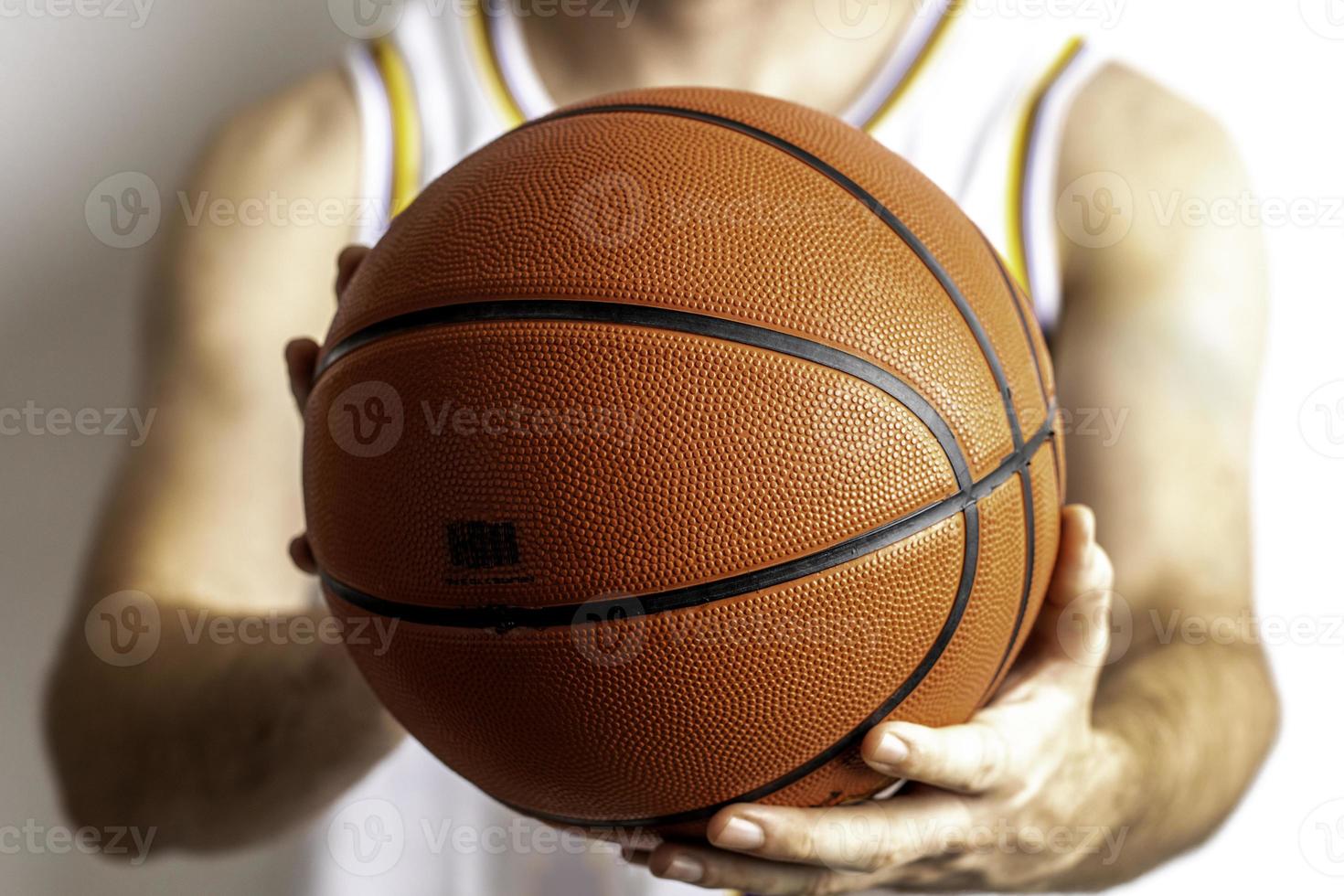 håller en basketboll foto