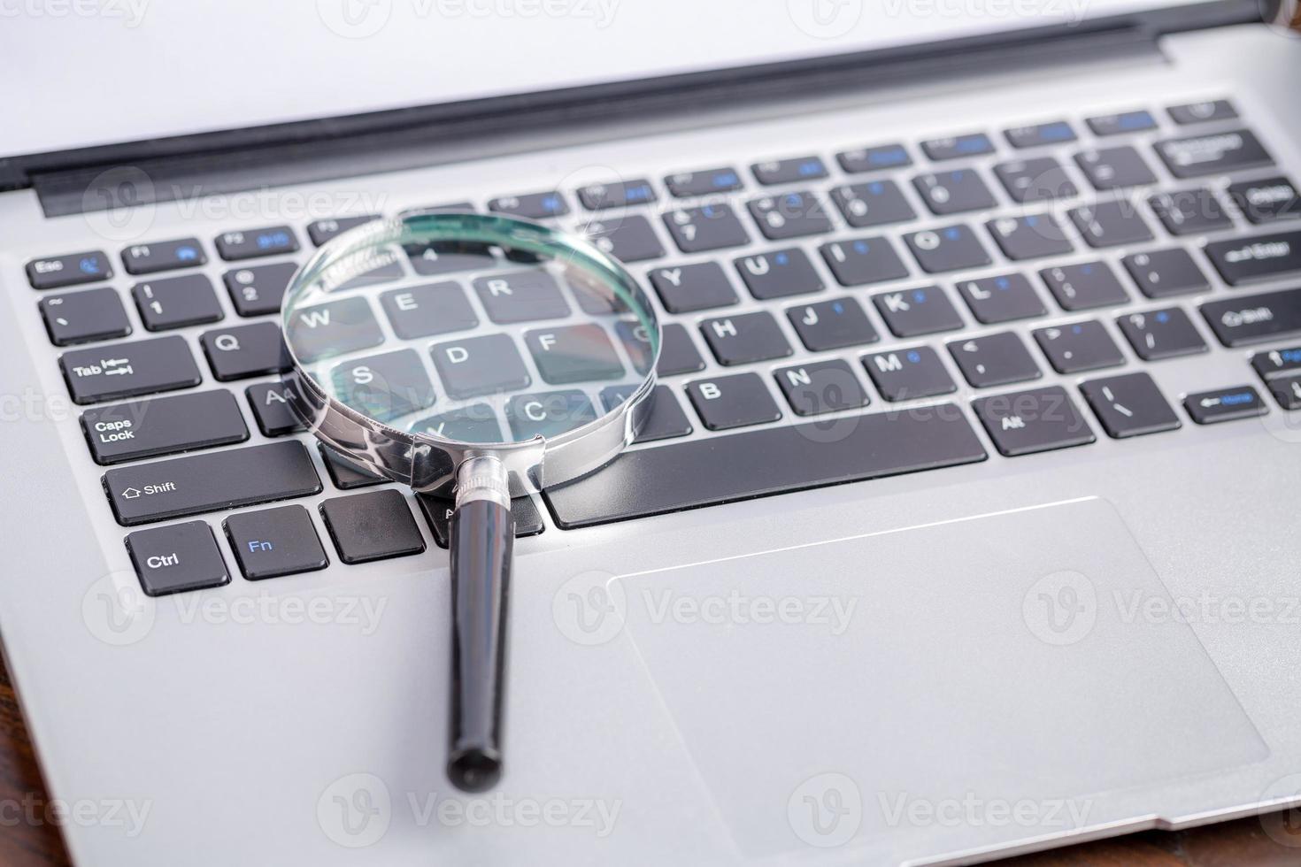 bärbar dator tangentbord med förstoringsglas, begreppet sökning foto
