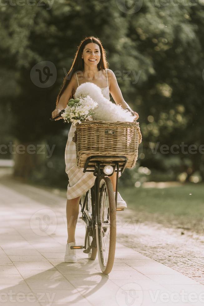 ung kvinna med vit bichon frise hund i korgen med elcykel foto