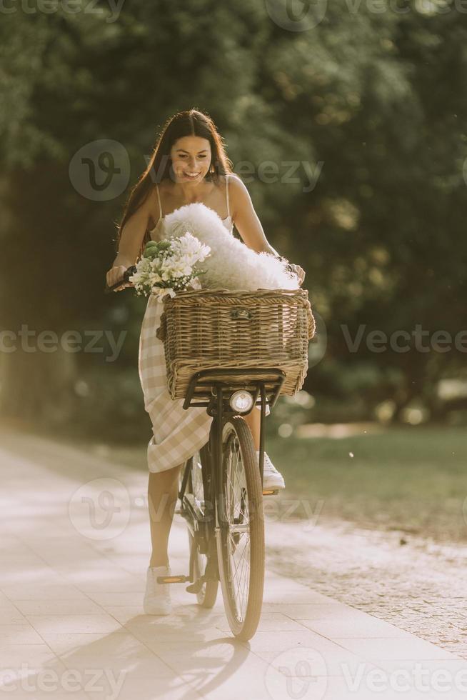 ung kvinna med vit bichon frise hund i korgen med elcykel foto