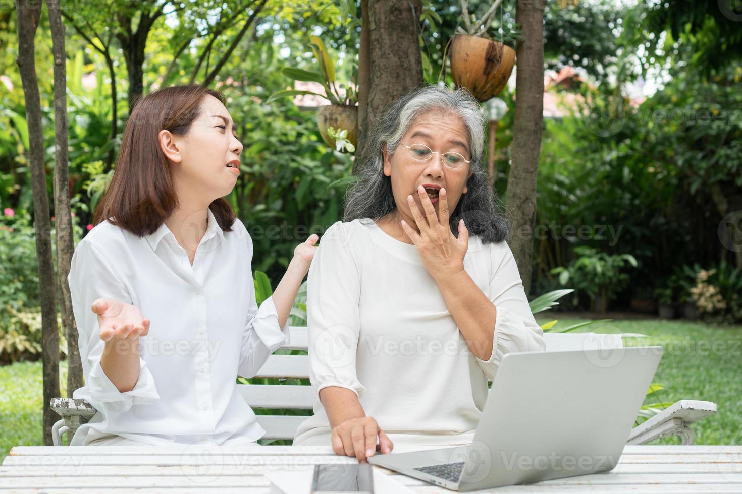 Asiatisk dotter undervisar gammal äldre kvinna att använda sociala medier online i en bärbar dator efter pensionering. begreppet lärande teknik och anpassning av äldre foto