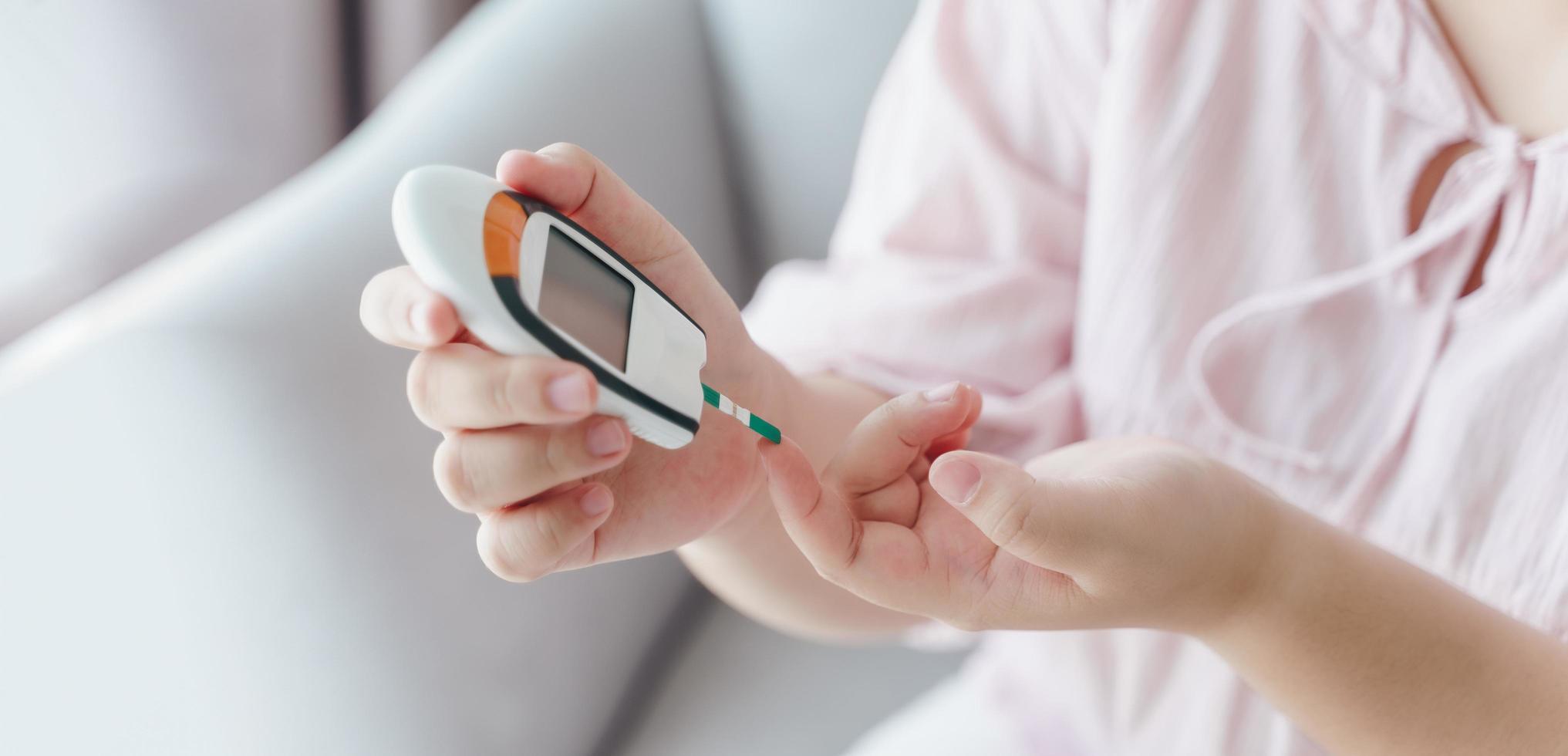 asiatisk kvinna som kontrollerar blodsockernivån med den digitala glukosmätaren, sjukvård och medicinsk, diabetes, glykemikoncept foto