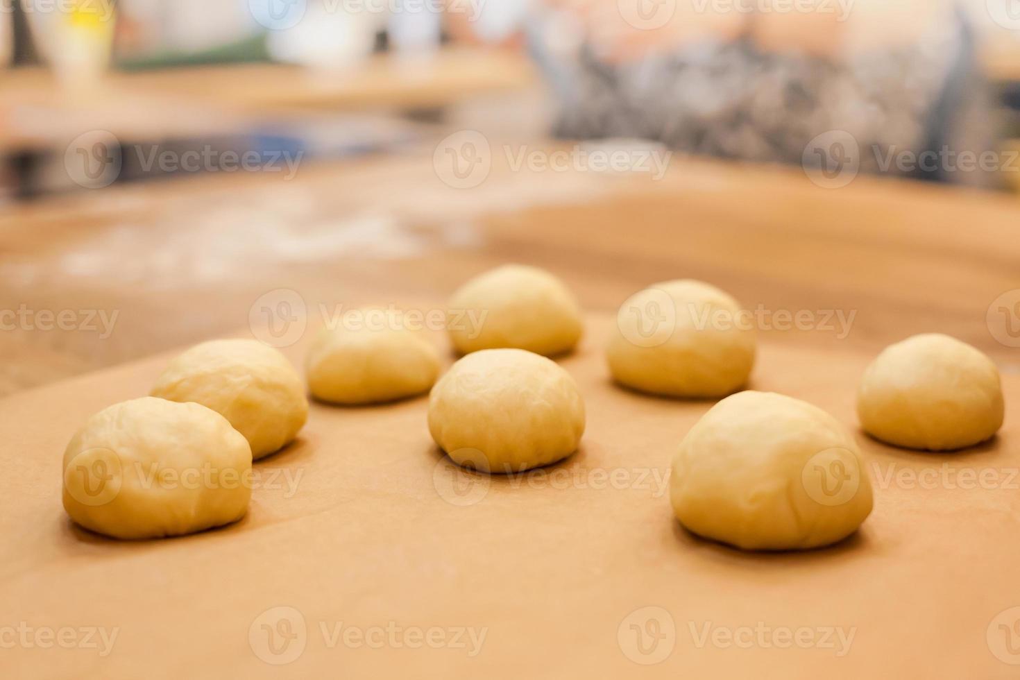 råa hemgjorda bullar på köksbordet i vardande foto