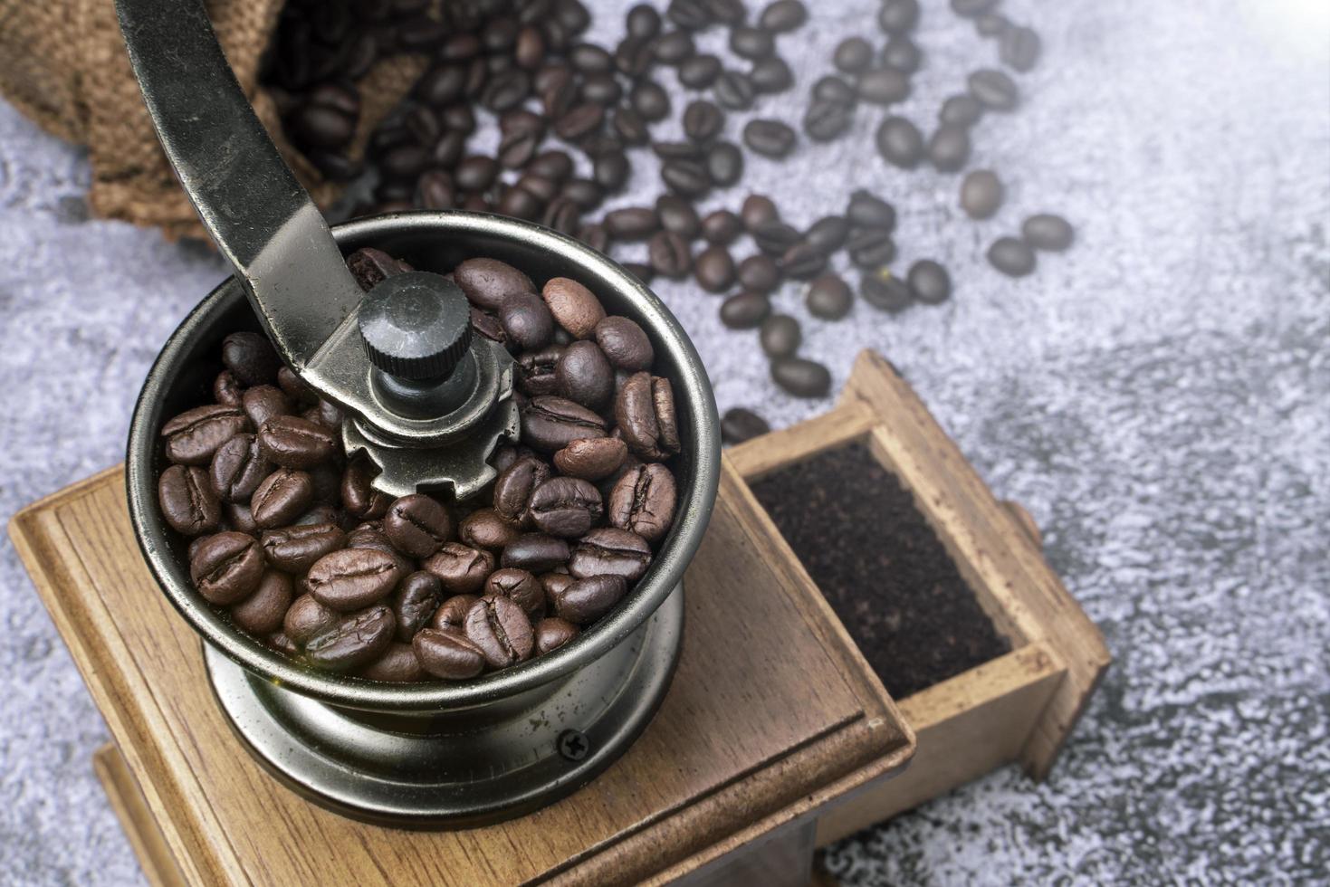 rostade kaffebönor i en antik handvev kaffekvarn. gammal retro handdriven kaffekvarn av trä och metall. mjukt fokus. foto