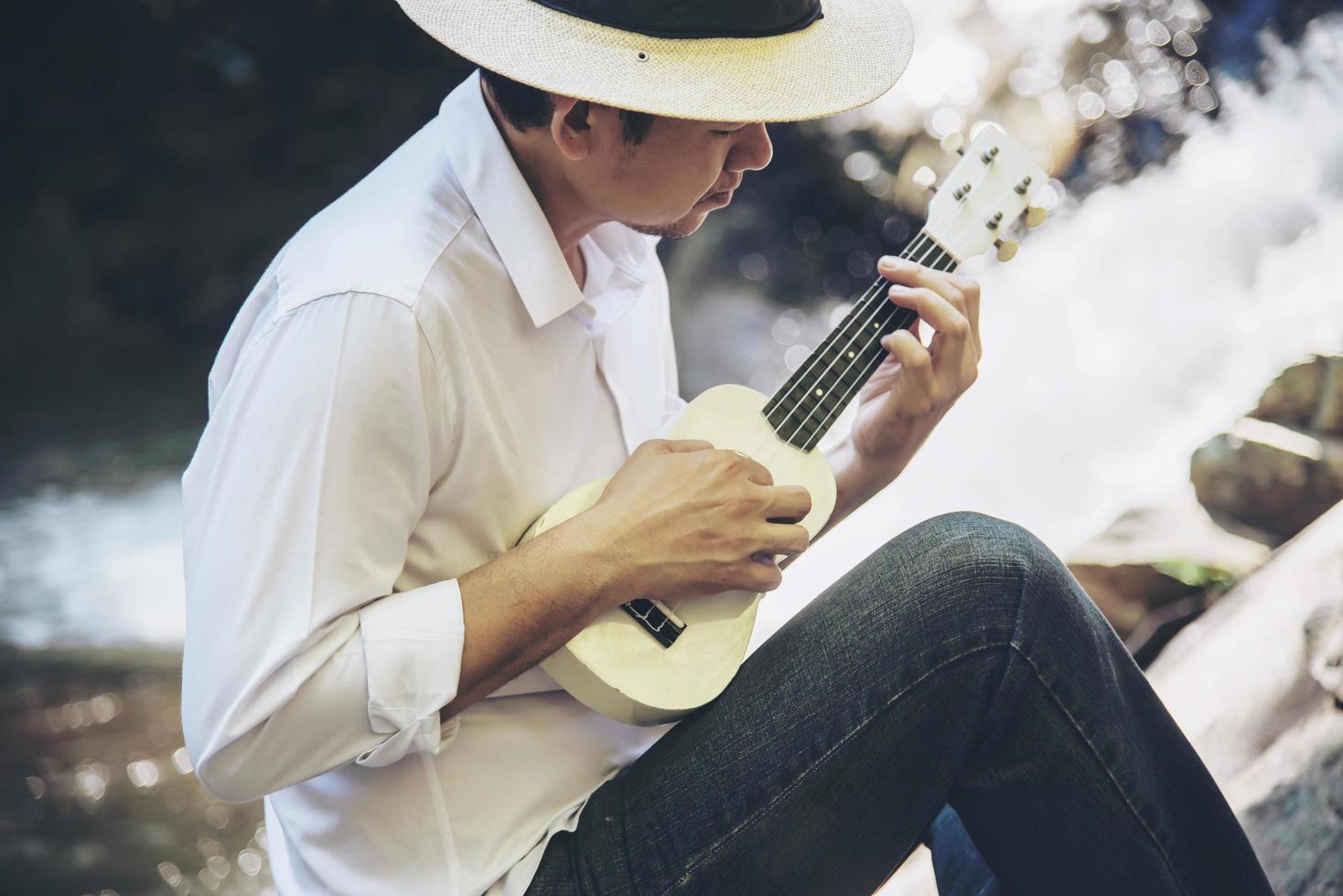 man spelar ukulele som är ny för floden - människor och musikinstrument livsstil i naturen koncept foto