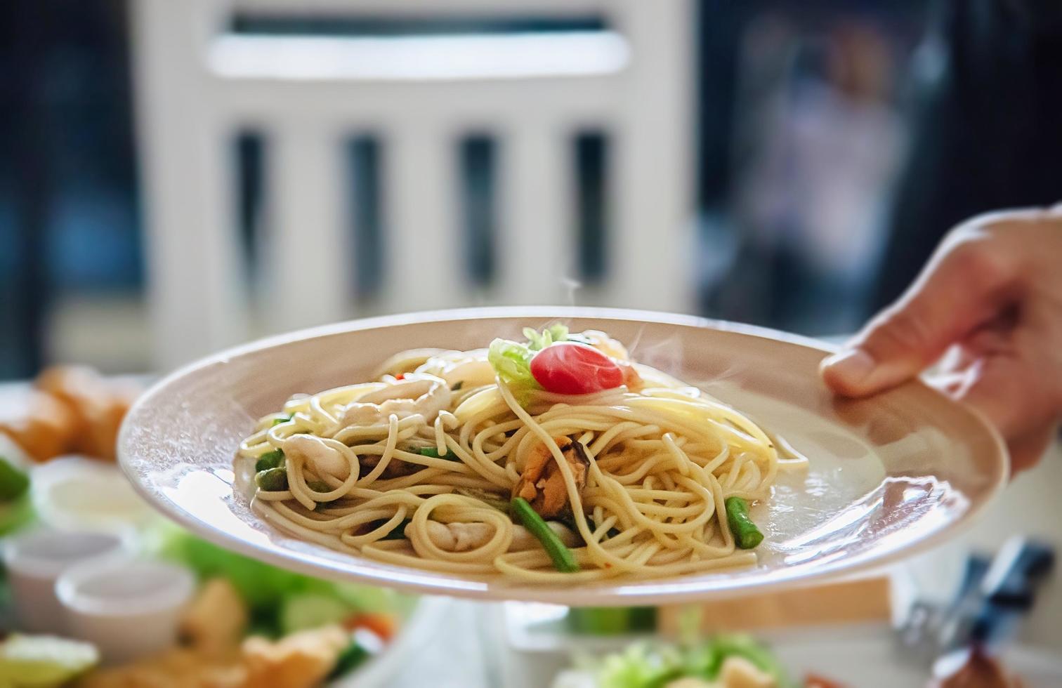 man serverar varm och kryddig spagetti med räkor - italiensk mat med människor koncept foto