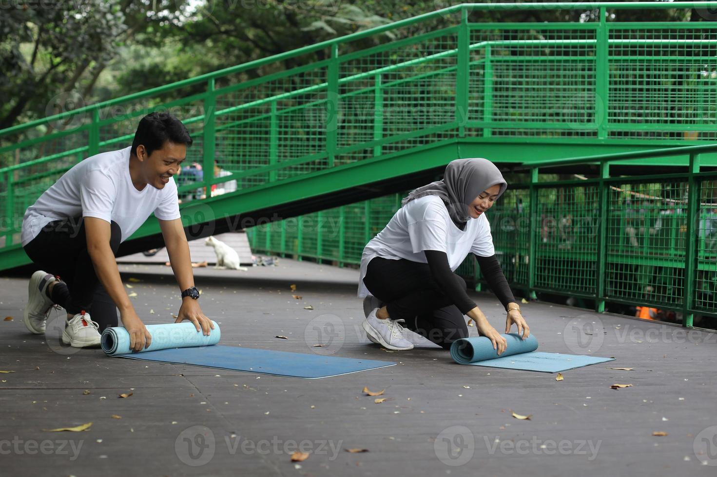 unga asiatiska par rullande yoga pilates matta efter workput i parken. hälsosam livsstil par koncept. foto