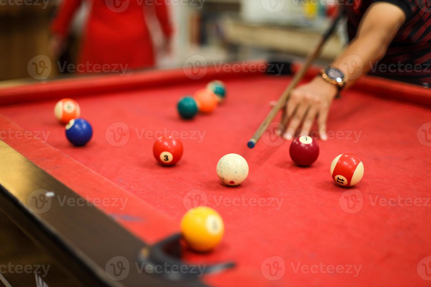 närbild av en mans hand som förbereder sig för att skjuta den vita bollen med en komplett uppsättning poolbollar foto