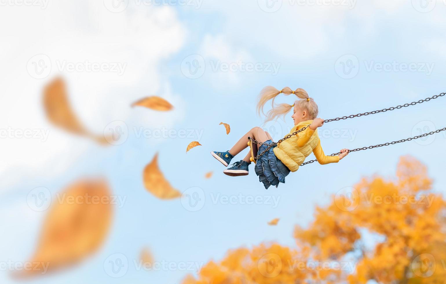 glad barn flicka rider på en gunga på hösten. foto