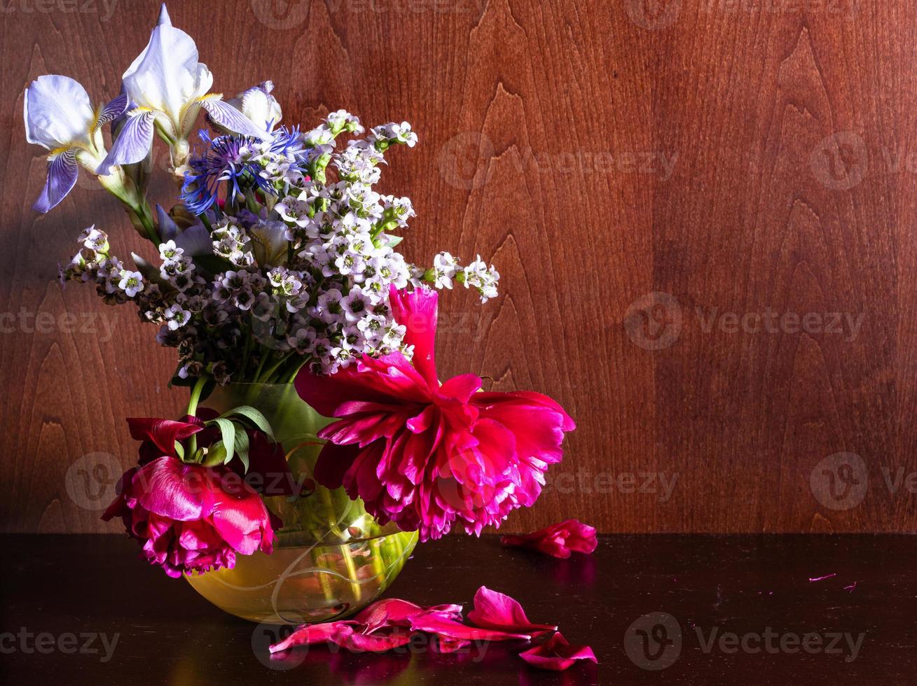 vissnade blommor i vas på mörkbrun bakgrund foto