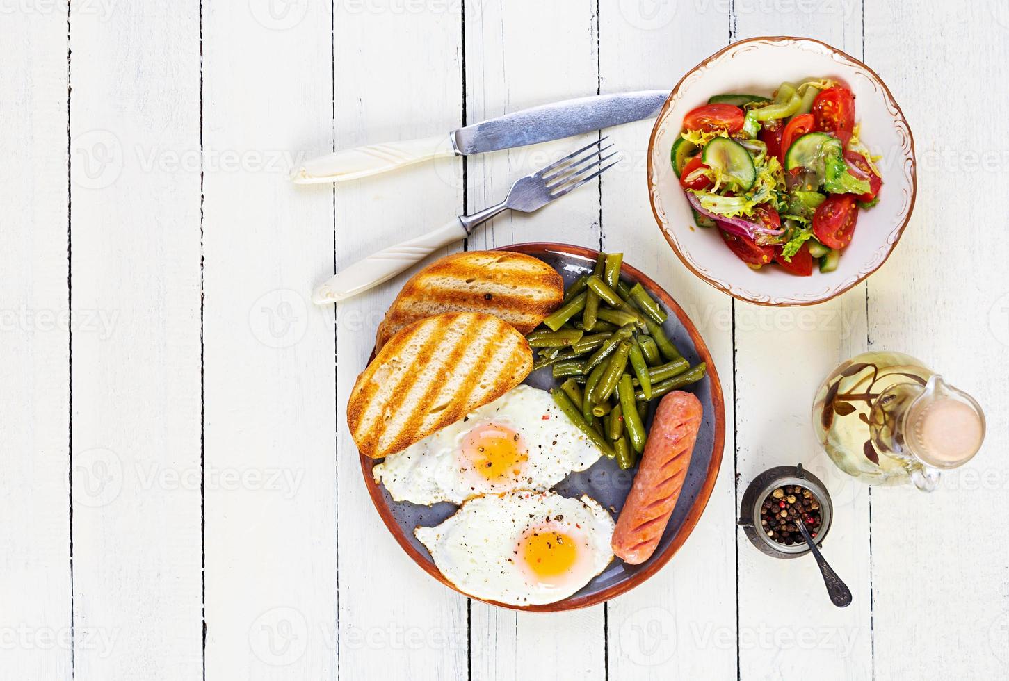 frukost med ägg, grillad korv, gröna bönor och rostat bröd på träbakgrund foto