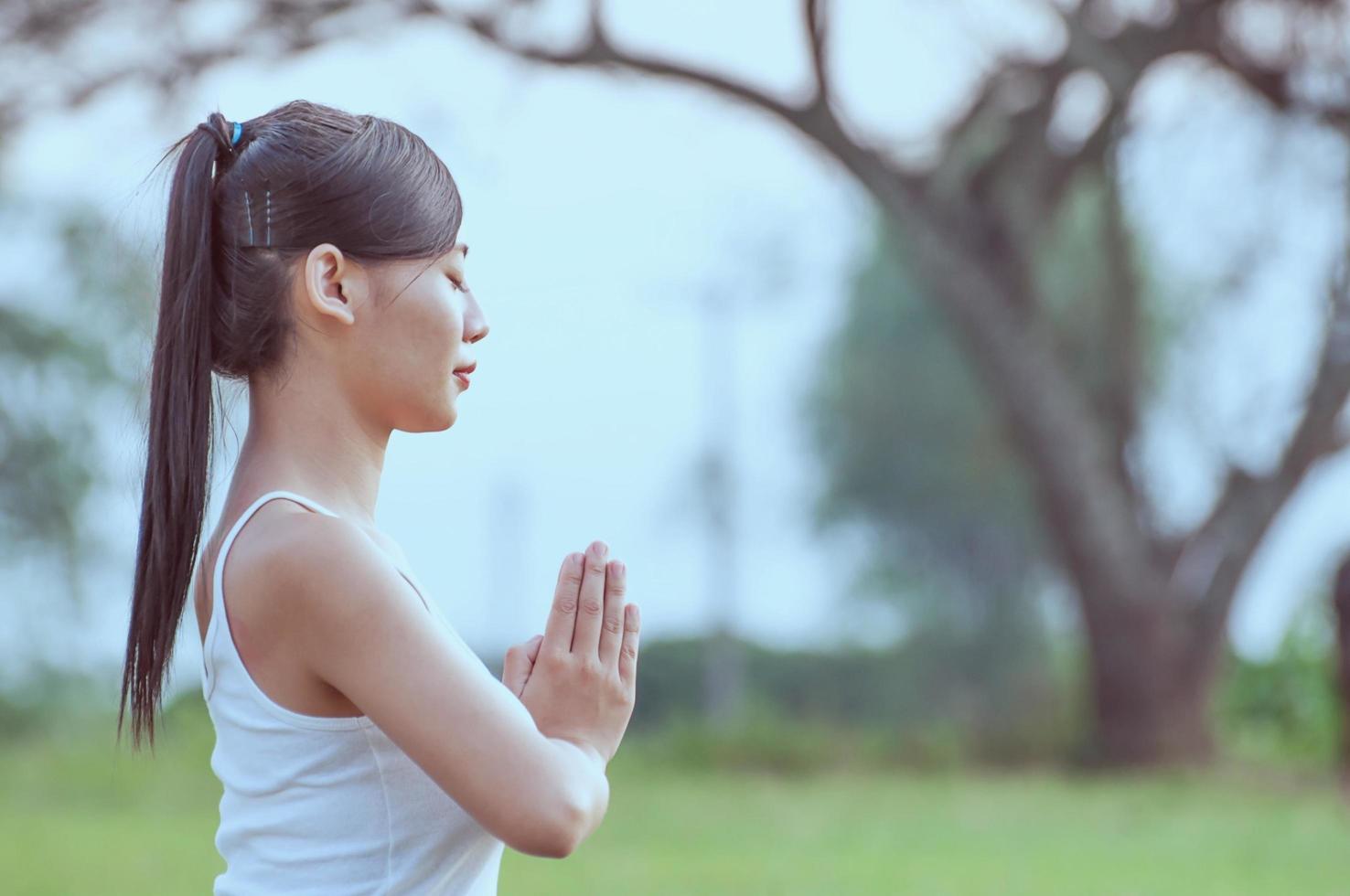 ung dam som gör yogaövningar i grönt fält utomhusområde som visar lugn fridfull i meditationssinnet - människor utövar yoga för meditation och träningskoncept foto