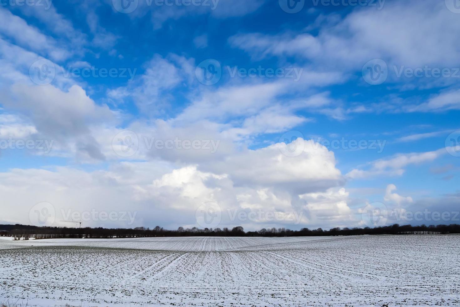 vackra moln på himlen tittar över ett snötäckt jordbruksfält. foto