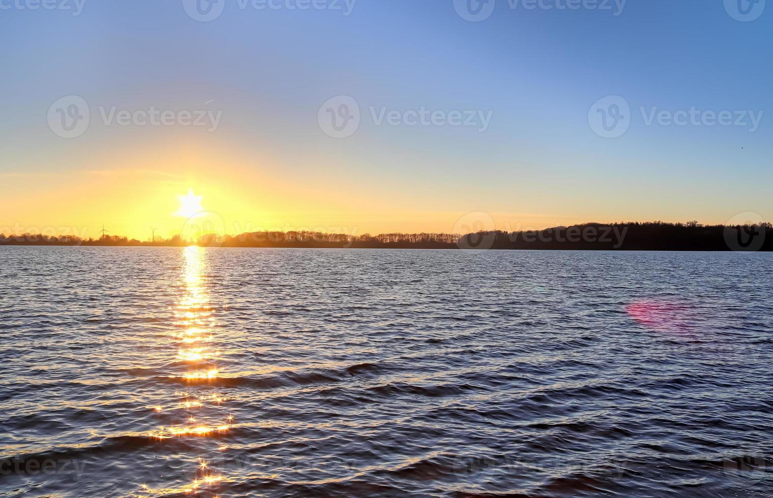 vacker och romantisk solnedgång vid en sjö i gula och orangea färger foto